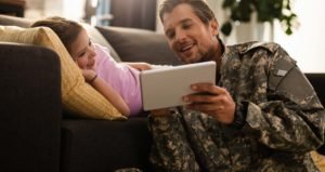 A veteran looking at a tablet with his daughter