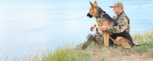 Soldier with dog looking out over water