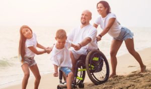 Family enjoying time on the beach after father's disability